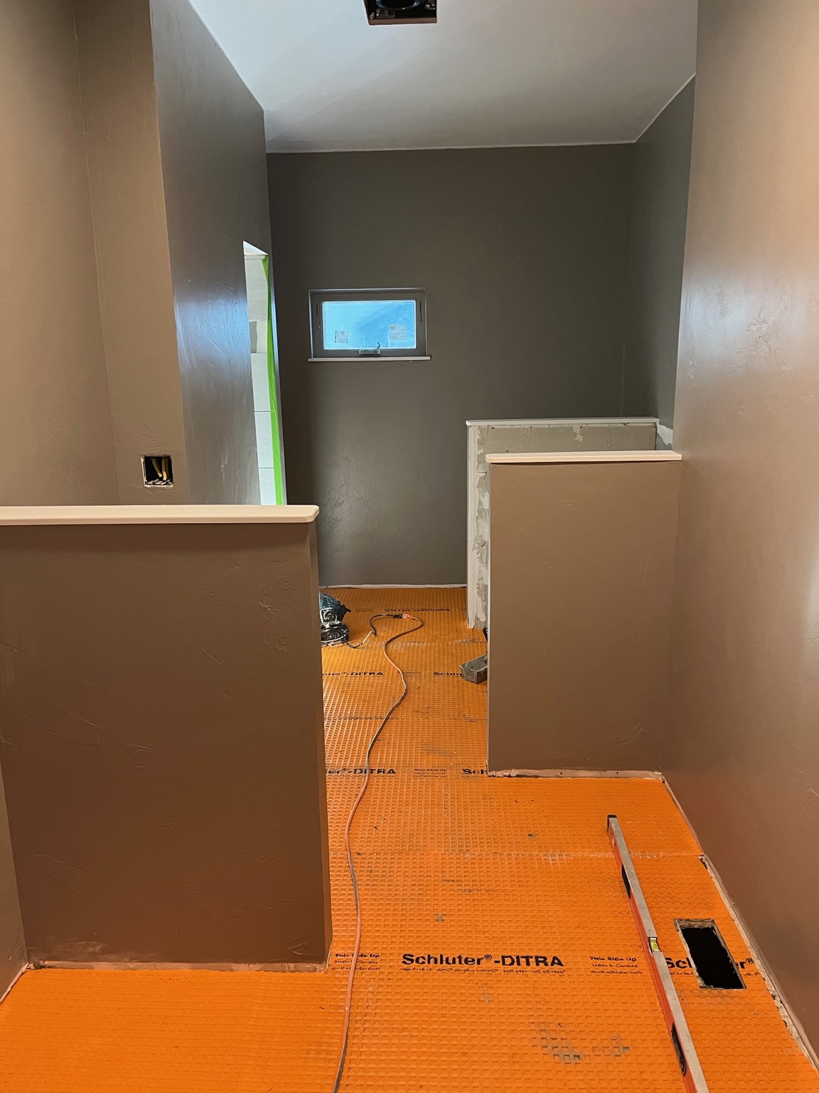 Schluter-DITRA uncoupling membrane installed across the bathroom floor