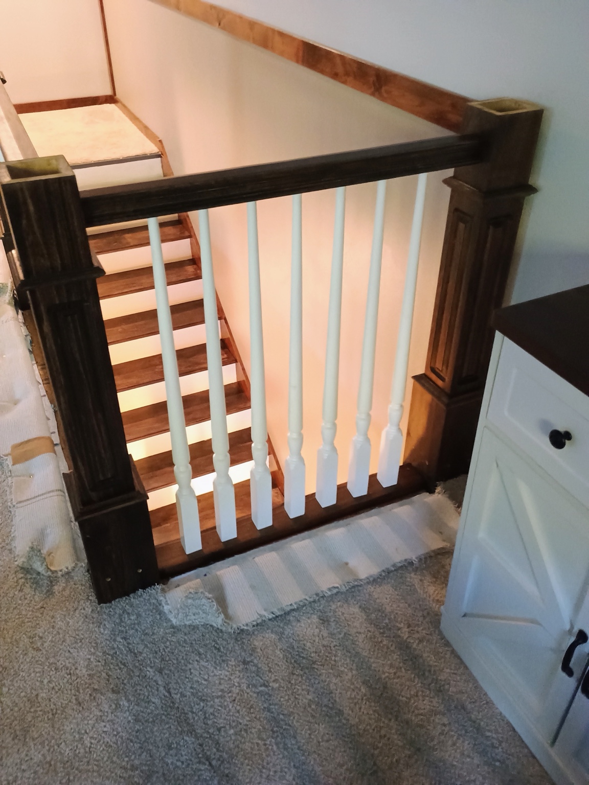 Dark-stained handrail and white balusters assembled at the landing