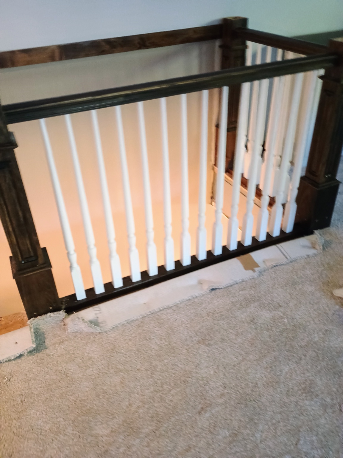 Completed landing guardrail with dark wood posts and white turned balusters