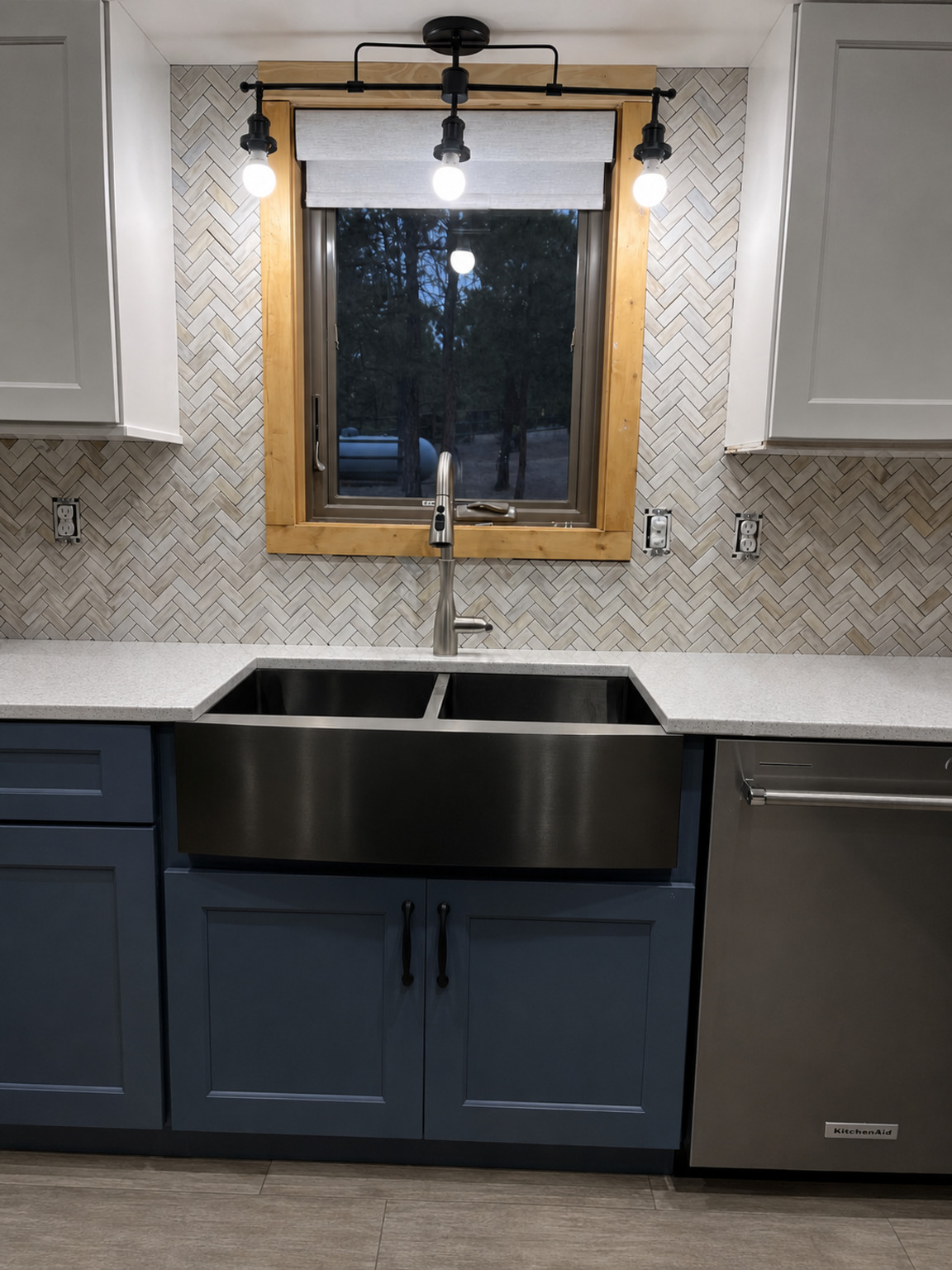 Marble herringbone tile backsplash surrounding a kitchen window and farmhouse sink