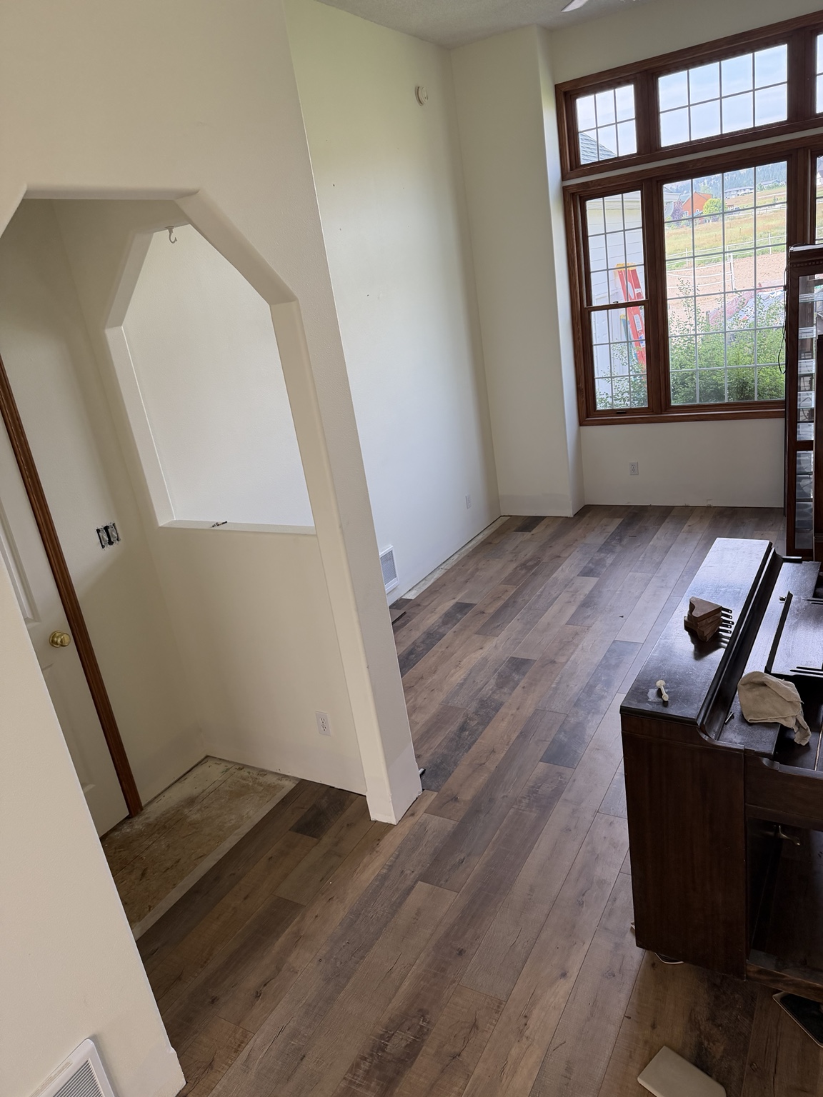 Completed laminate flooring installation across a bright living space with tall wood-trimmed windows