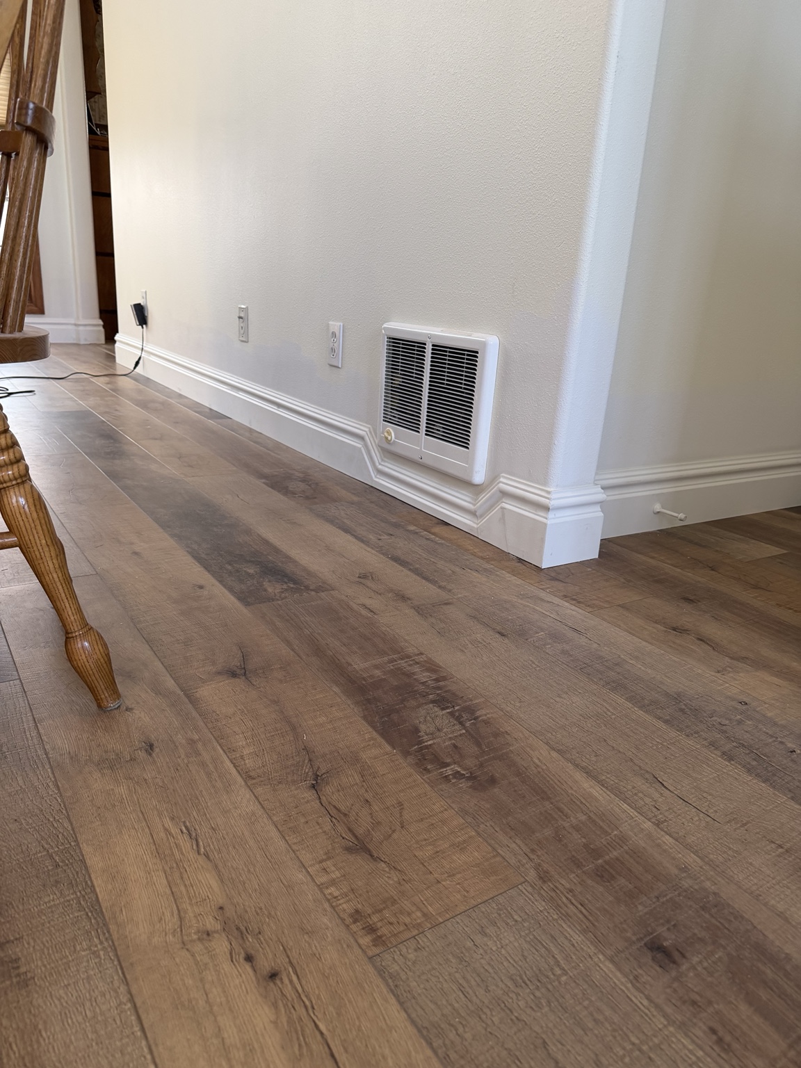 Custom baseboard profile fitted precisely around a wall heater and corner
