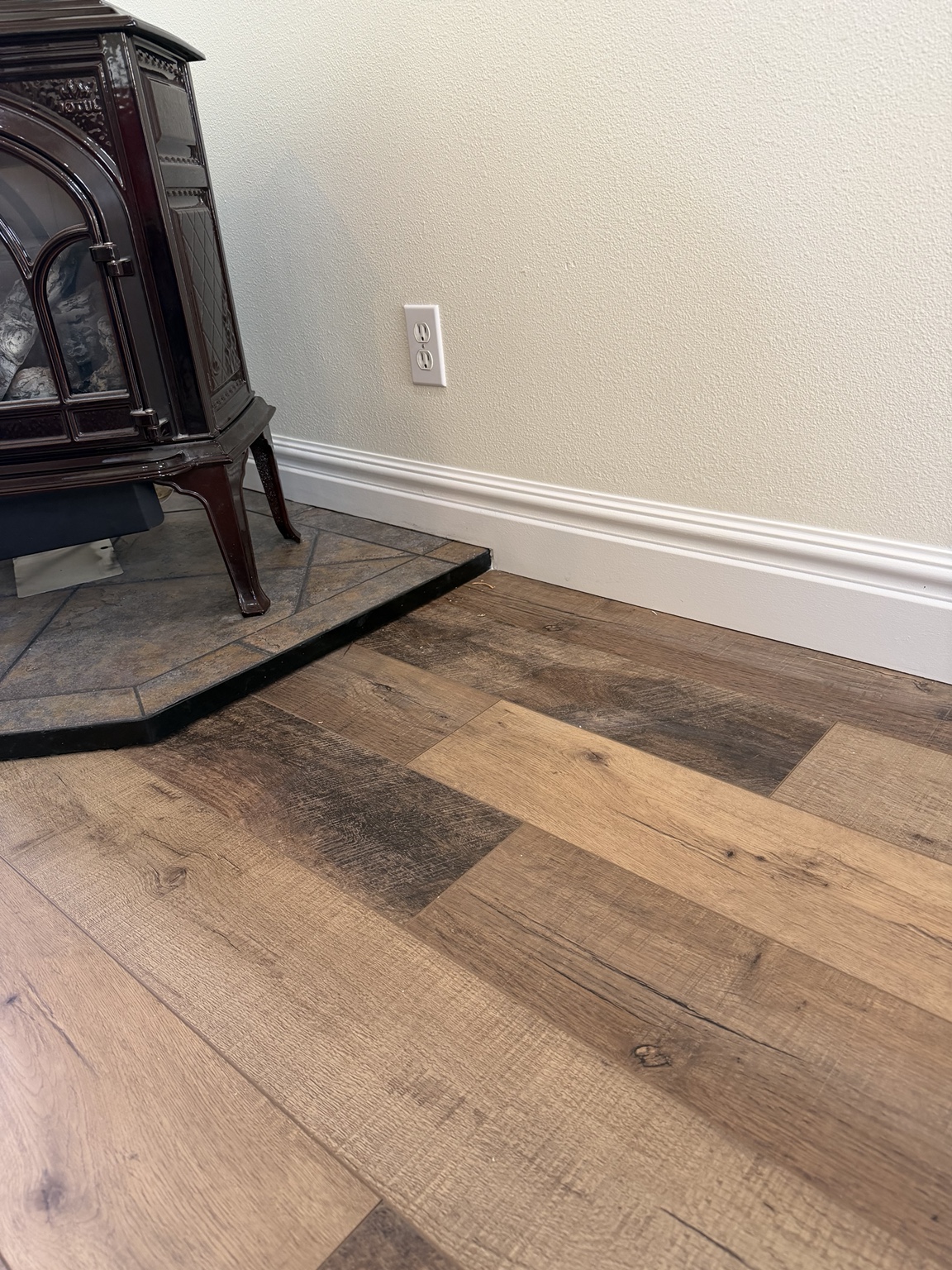 Laminate flooring and custom baseboard finished cleanly at the raised hearth