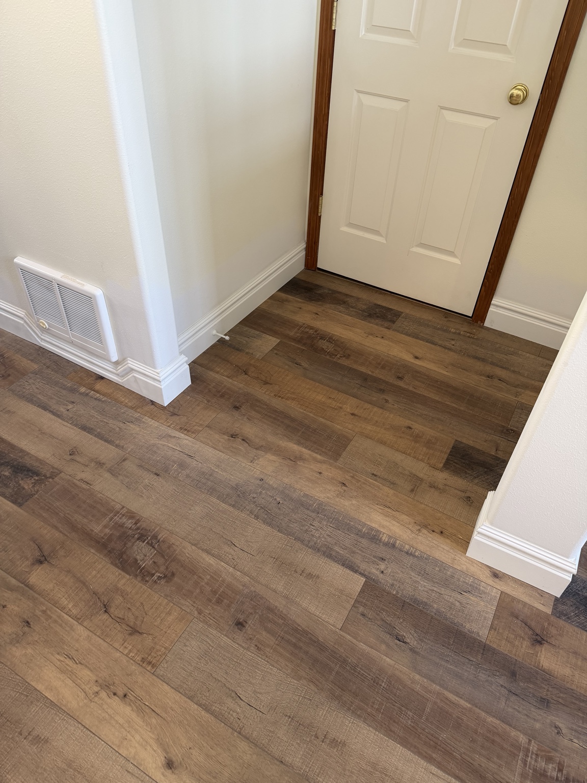 Wide finished view of the laminate flooring and custom baseboard across the open entry area